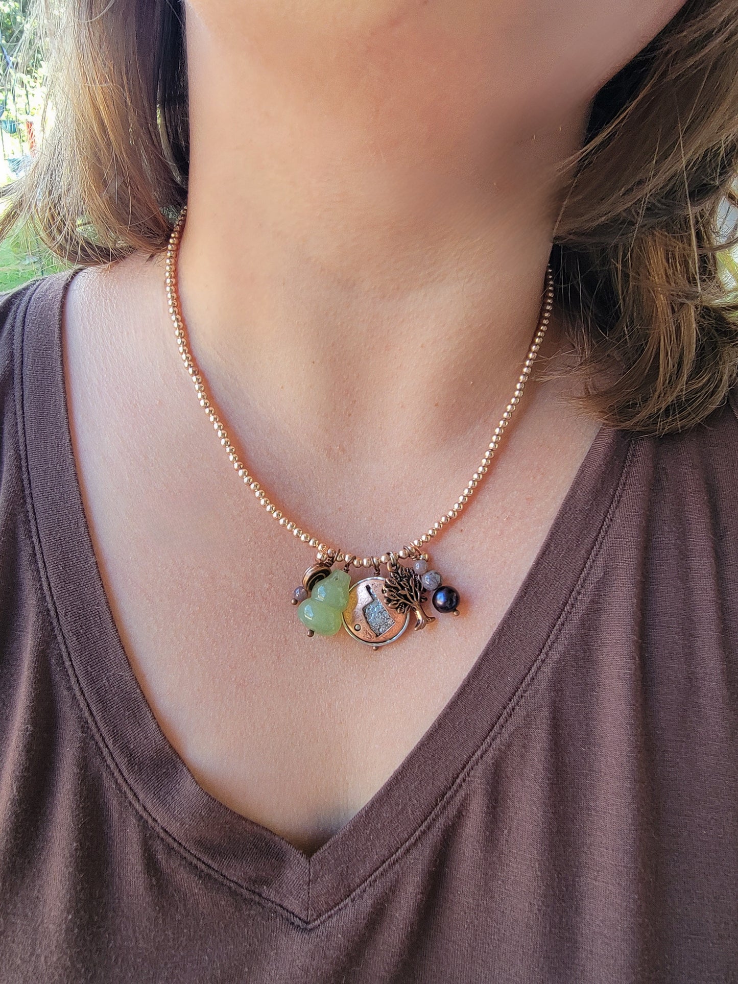 Necklace with colorful beads worn by a person in a brown shirt.